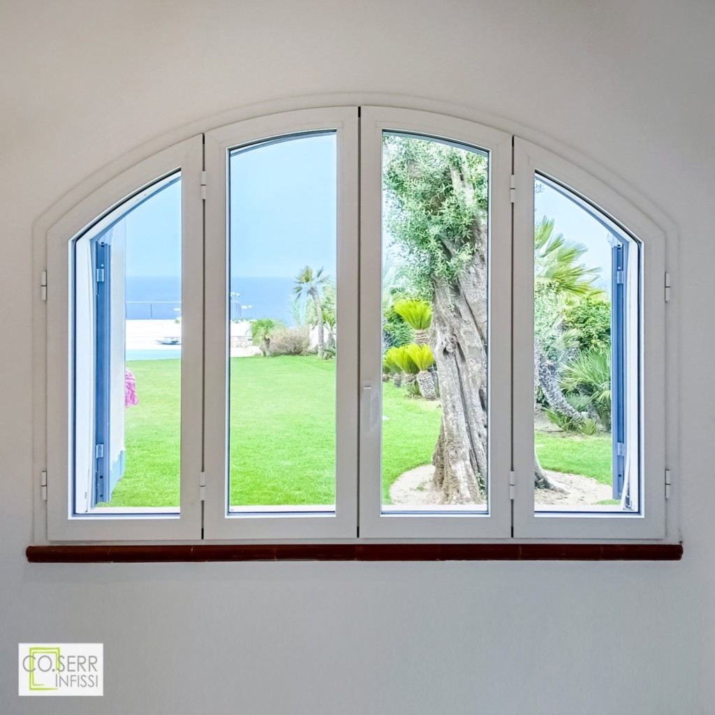 finestra ad arco di quattro ante in alluminio con vista interna su giardino con ulivo