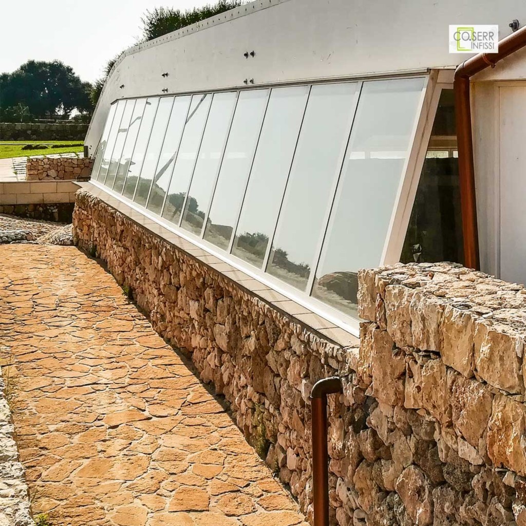 Grandi infissi in alluminio installati presso il resort Capo Campolato ad Augusta, con struttura inclinata e vista panoramica.

