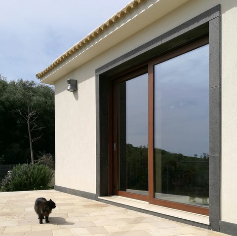 Porta finestra scorrevole con sistema alzante in allumnio legno per villa ad Augusta Porta finestra alzante scorrevole in alluminio effetto legno con gatto che si specchia sul vetro ad augusta